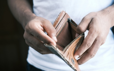Eine Person blickt in ihren leeren Geldbeutel. 